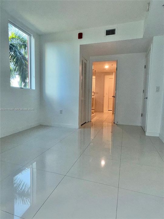 Polished porcelain tile flooring, large-format window with exterior foliage, and louvered closet doors