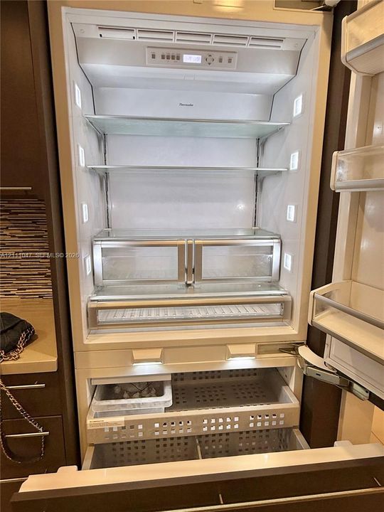 Built-in panel-ready refrigerator featuring integrated LED side-wall lighting, adjustable glass shelving, clear-front produce drawers, and pull-out freezer storage