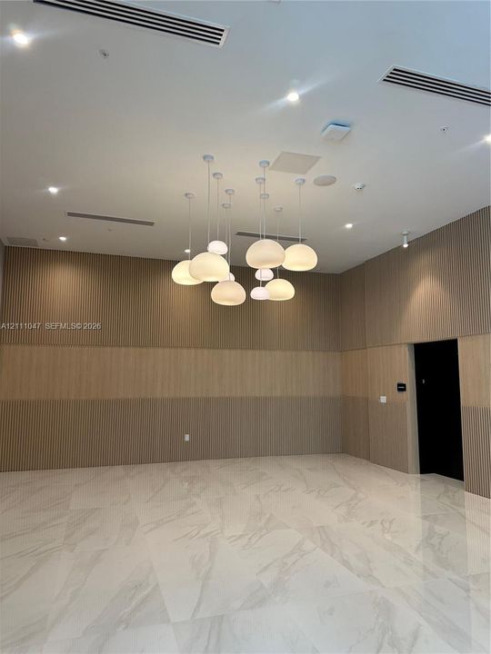 Textured wood-slat wall paneling, large-format stone-finish flooring, and a multi-pendant spherical light fixture