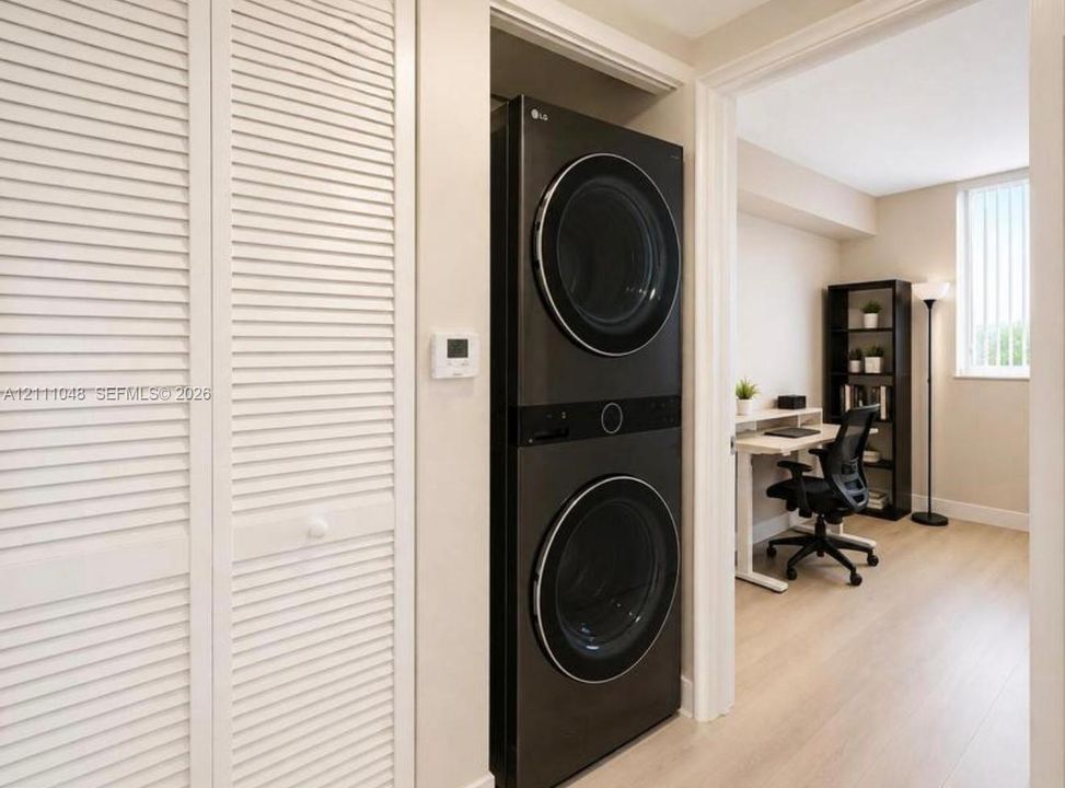 Integrated laundry closet featuring a stacked washer and dryer unit, louvered bi-fold doors, and wood-finish flooring