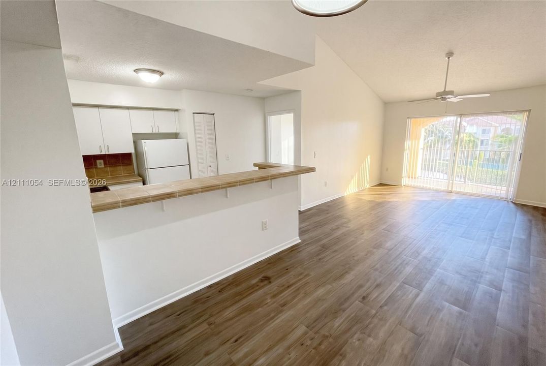 Open-concept kitchen featuring a tile-topped breakfast bar, wood-finish flooring, vaulted ceilings, and glass sliding doors
