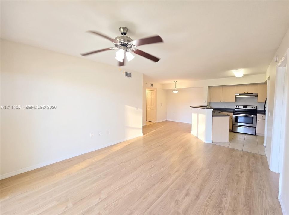 Wood-finish flooring, ceiling fan with integrated lighting, kitchen featuring a breakfast bar, flat-panel cabinetry, and stainless steel range