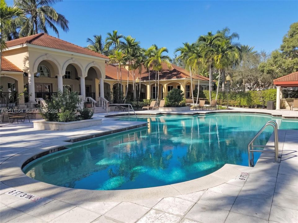 In-ground swimming pool featuring a tiled deck, metal handrails, and arched masonry architecture
