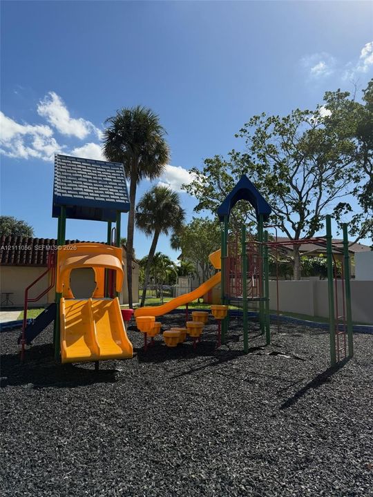 Outdoor recreational area featuring a multi-level climbing structure, dual slides, stepping platforms, and rubberized ground cover