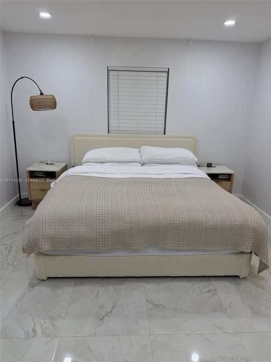 Large-format tile flooring, recessed ceiling lighting, and horizontal window blinds