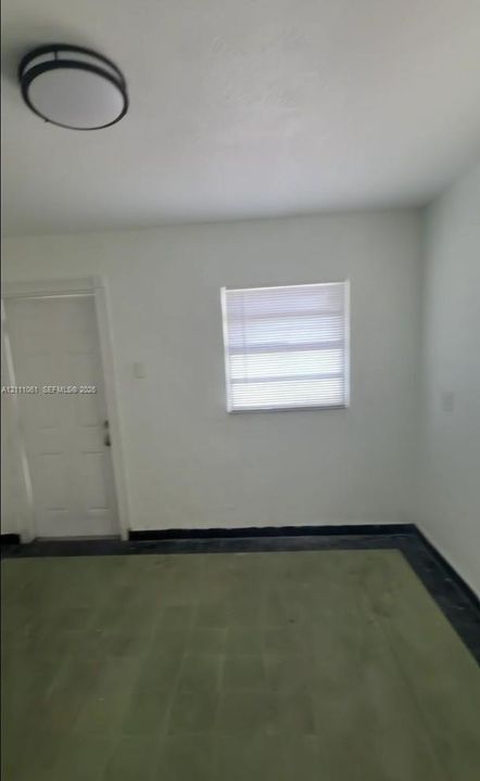 Interior space featuring a multi-panel door, a window with installed blinds, ceiling-mounted light fixture, and tile flooring