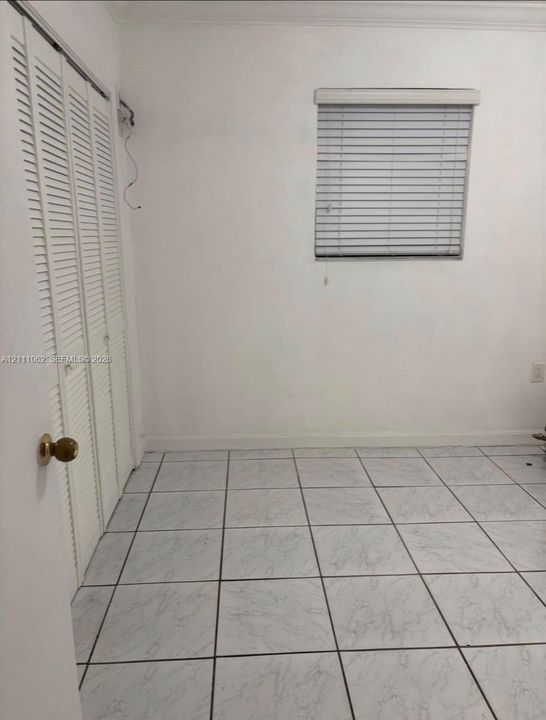 Tile flooring, bi-fold louvered closet doors, and window with fitted blinds