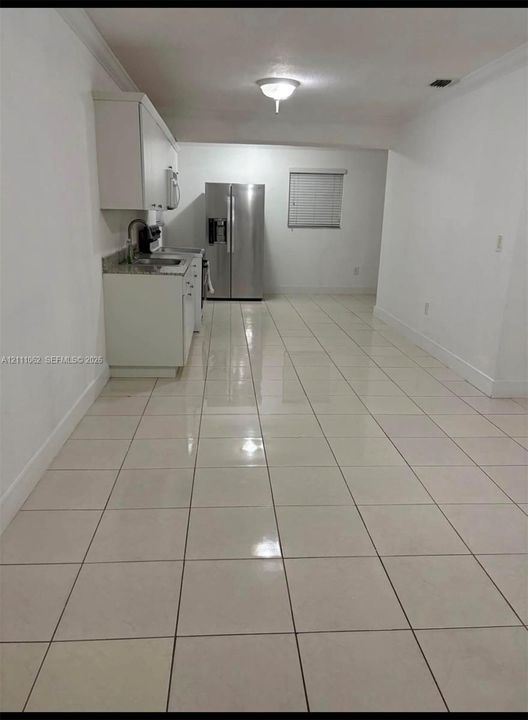 Kitchen featuring white cabinetry, stone-finish countertops, stainless steel refrigerator, and ceramic tile flooring