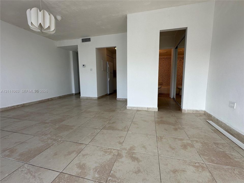 Open-concept interior featuring large-format ceramic tile flooring, neutral wall finishes, and a contemporary architectural pendant light fixture