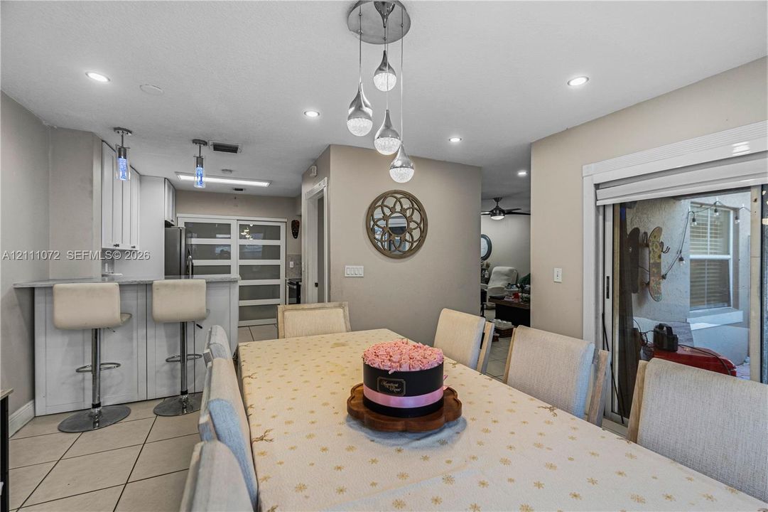 Dining area featuring recessed lighting, a modern multi-pendant light fixture, tile flooring, and sliding glass doors with access to an exterior area