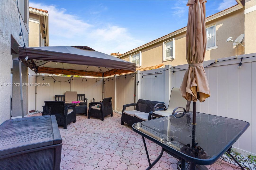 Enclosed rear patio featuring concrete paver flooring and full-height vinyl privacy fencing