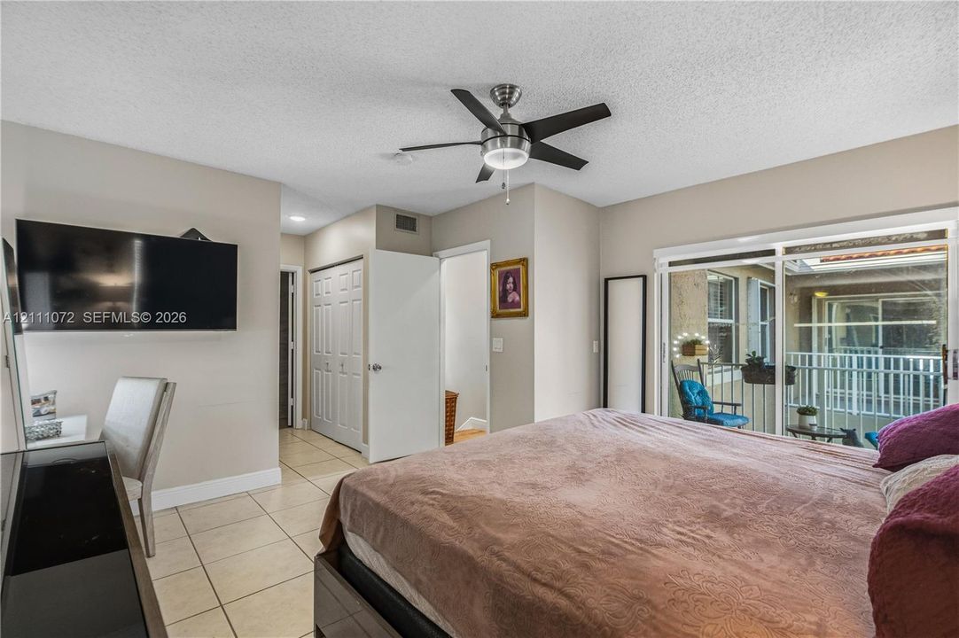 Sliding glass door, neutral tile flooring, built-in ceiling fan with integrated lighting, and multi-panel interior closet doors