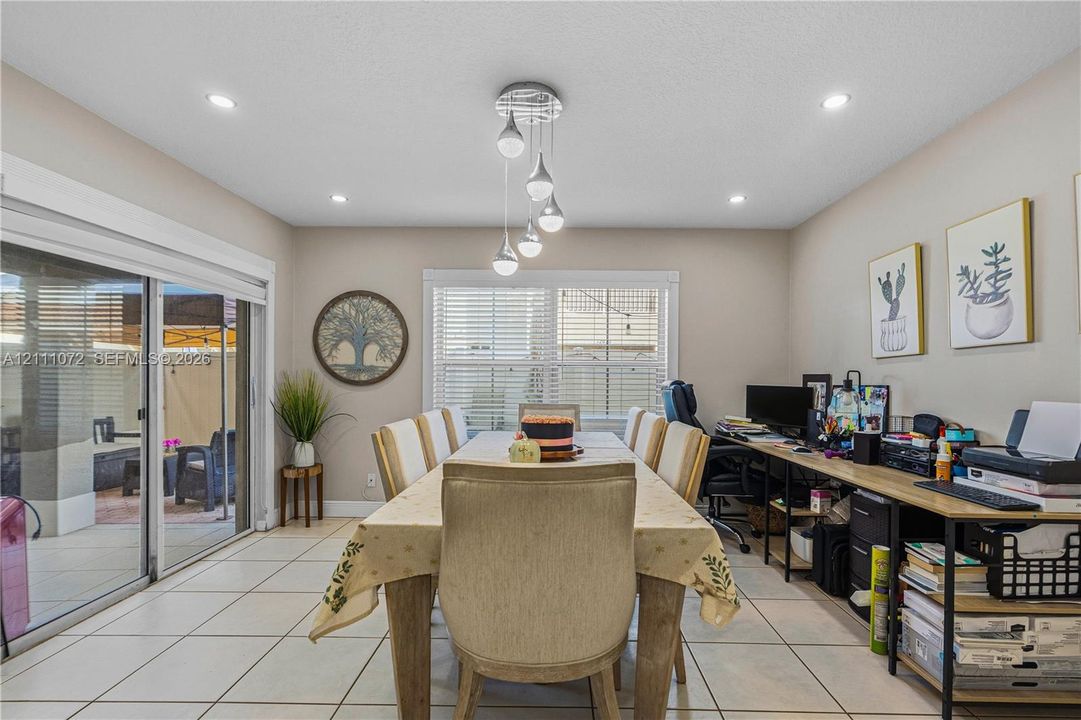 Dining area featuring large-format tile flooring, multi-pendant contemporary lighting, recessed ceiling lights, and wide sliding glass doors