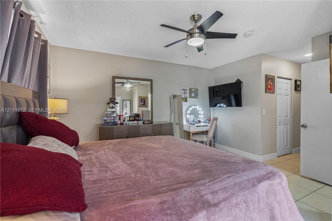 Room featuring ceramic tile flooring, a multi-blade ceiling fan with integrated lighting, and a bi-fold closet door