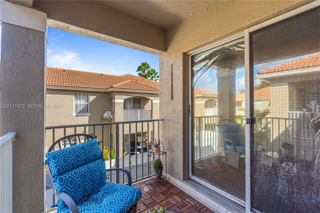 Covered balcony featuring wood-finish decking, metal railings, and a sliding glass door