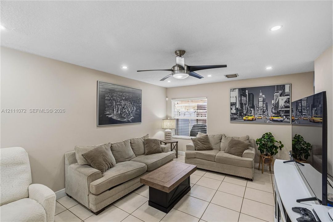 Neutral-toned interior space featuring large-format tile flooring, recessed lighting, and a modern metal ceiling fan