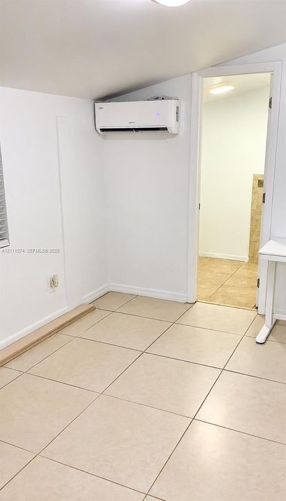 Wall-mounted ductless climate control system, neutral ceramic tile flooring, and vaulted ceiling