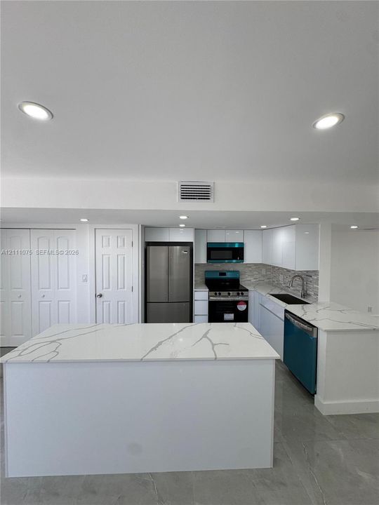Kitchen featuring white cabinetry, stone-finish countertops with veining, a central island, recessed lighting, and stainless steel appliances