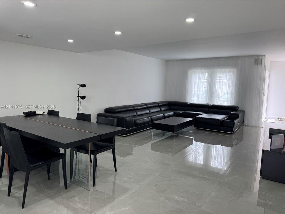 Polished large-format floor tile, recessed ceiling lighting, and floor-to-ceiling sheer window treatments