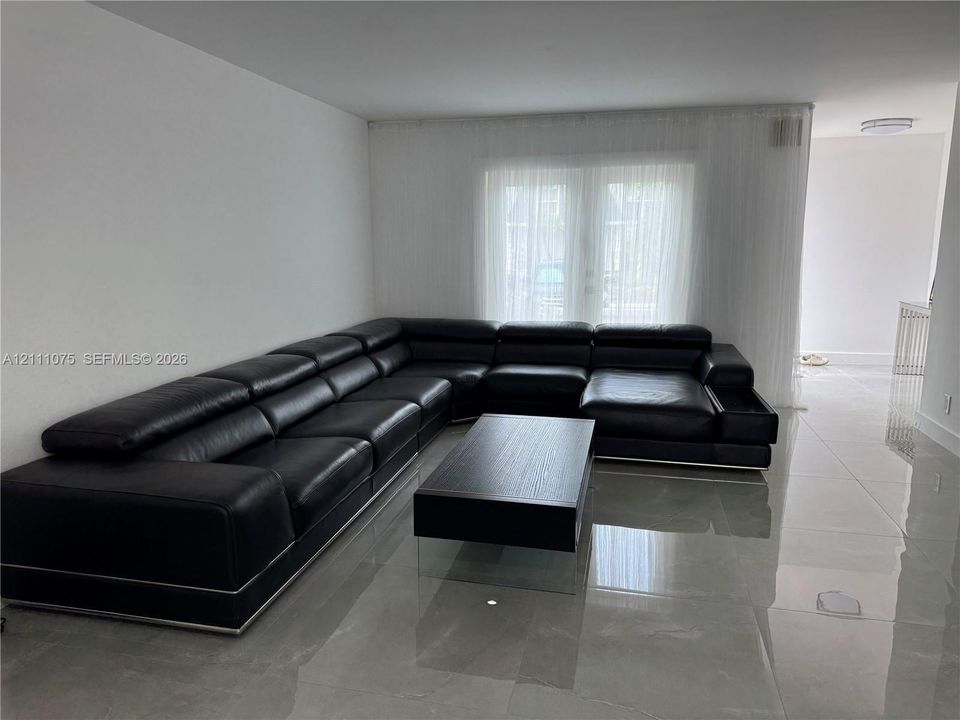 Large format light-colored tile flooring, double glass panel doors, and neutral wall tones