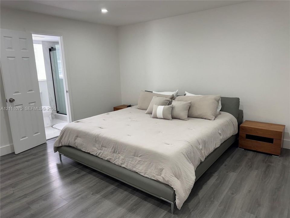 Neutral-toned bedroom featuring wood-finish flooring, recessed lighting, and a six-panel interior door