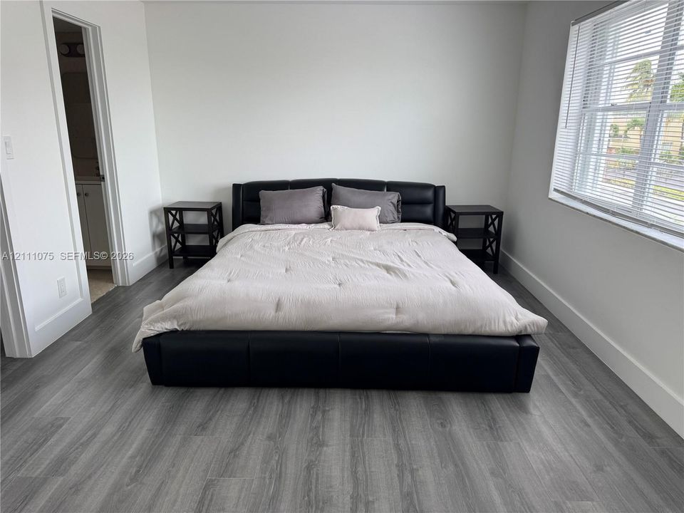 Room featuring wood-finish flooring, neutral walls, and a window with horizontal blinds