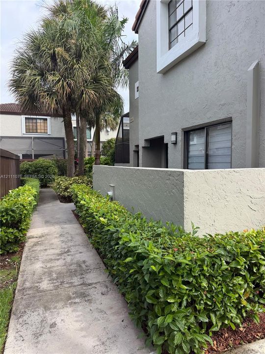 Stucco exterior featuring a private courtyard wall, concrete walkway, and mature landscaping