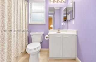 Bathroom featuring a white vanity cabinet with a solid surface countertop, an undermount sink with a metallic faucet, a large rectangular mirror, and an over-the-mirror multi-bulb light fixture