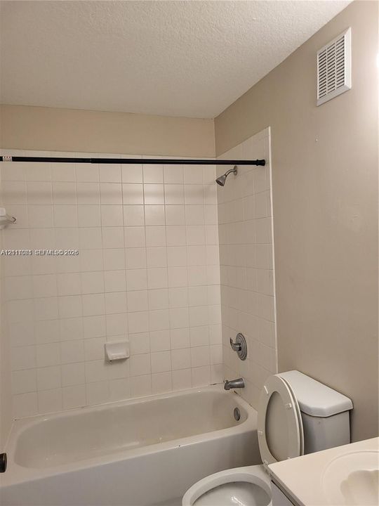 Bathtub with white ceramic tile surround and integrated soap dish, chrome shower head, and chrome faucet fixture