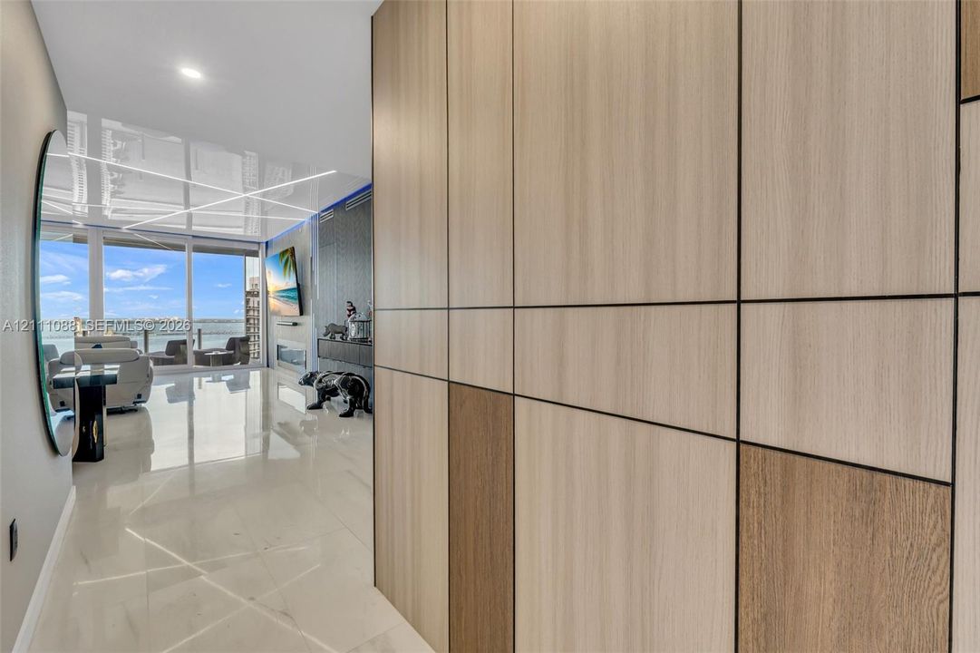 Floor-to-ceiling multi-tonal wood-finish paneling with integrated reveals, polished stone-finish flooring, and expansive floor-to-ceiling glass sliding doors