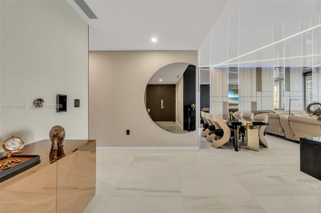 Large-format light-toned flooring, circular interior wall cutout, linear ceiling lighting, and integrated wall paneling