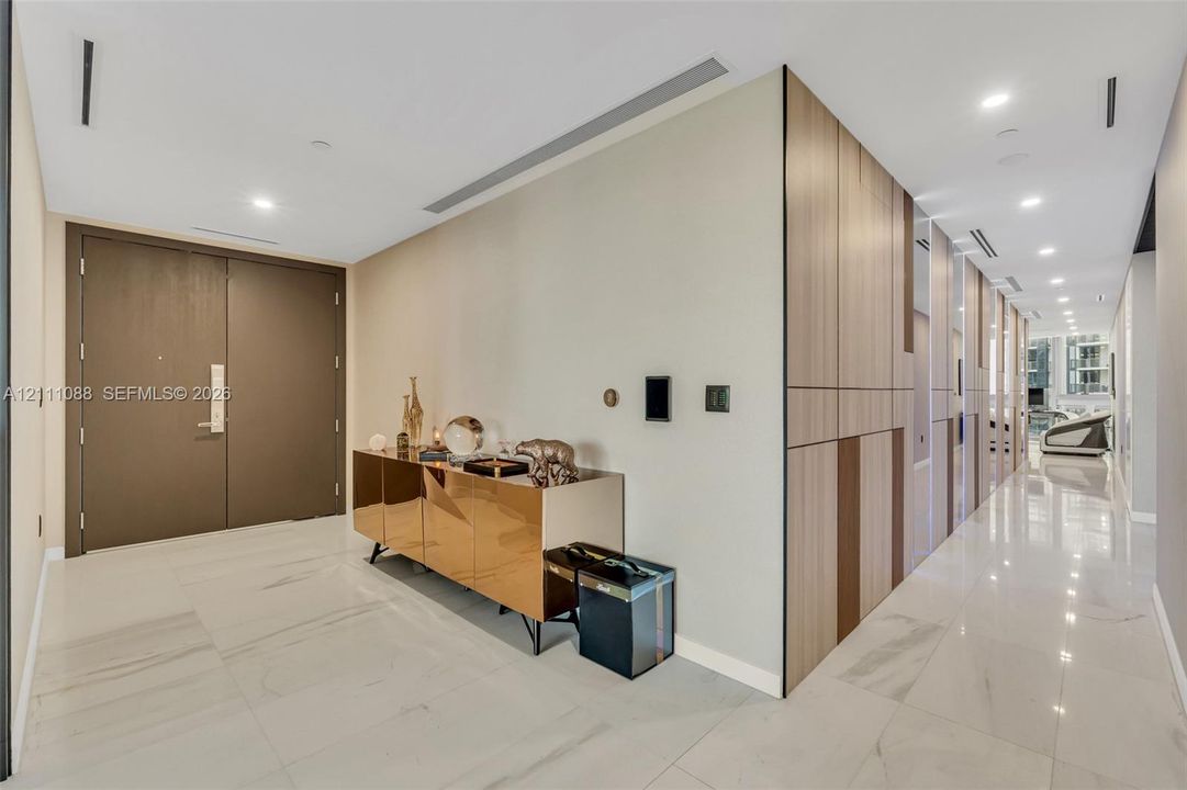 Entryway featuring large-format stone tile flooring, floor-to-ceiling wood-finish paneling, recessed ceiling lighting, and custom double doors