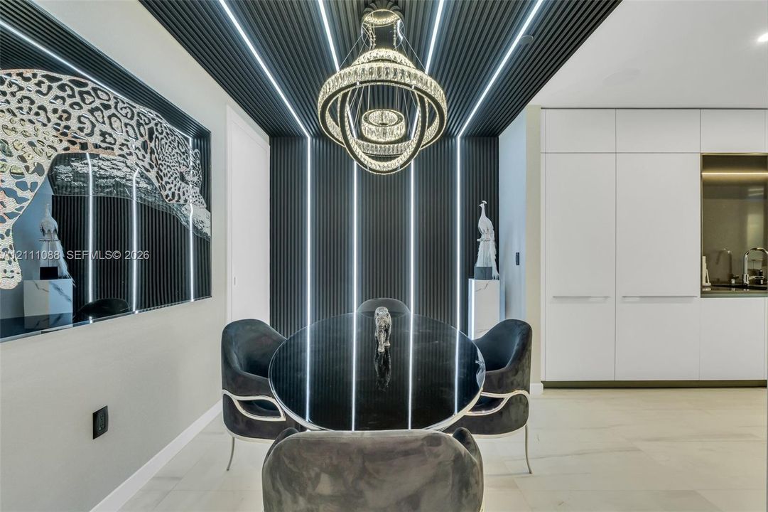 Black slatted wall paneling with integrated vertical LED lighting, three-tier crystal chandelier, high-gloss white cabinetry, and light-toned large-format flooring