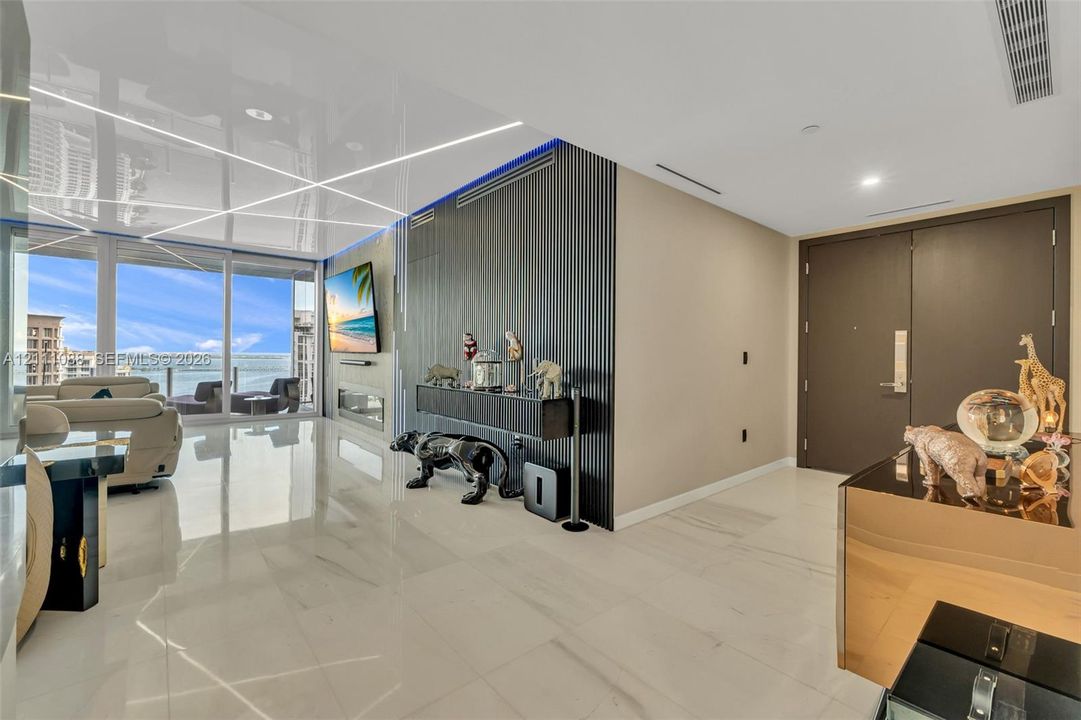 Living space featuring floor-to-ceiling glass sliding doors, high-gloss finish flooring, a linear built-in fireplace, and a textured, vertical-slat accent wall with integrated recessed lighting