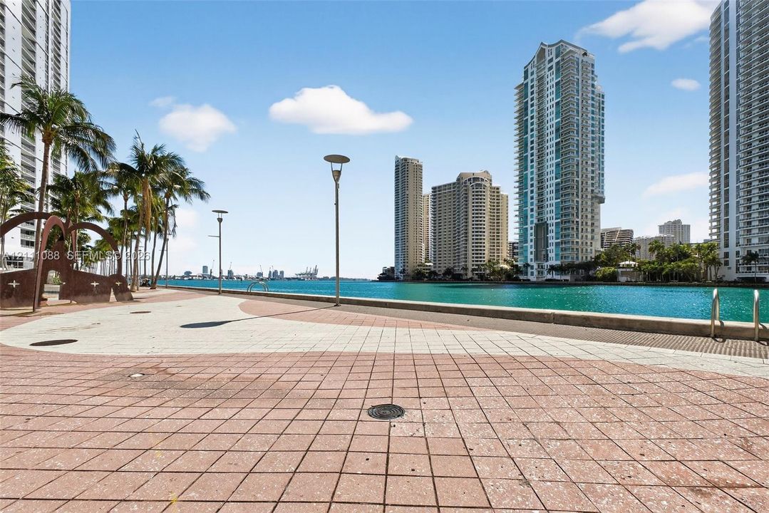 Waterfront promenade featuring paved stone tiling, custom metal sculptures, integrated exterior lighting, and direct access to the waterway