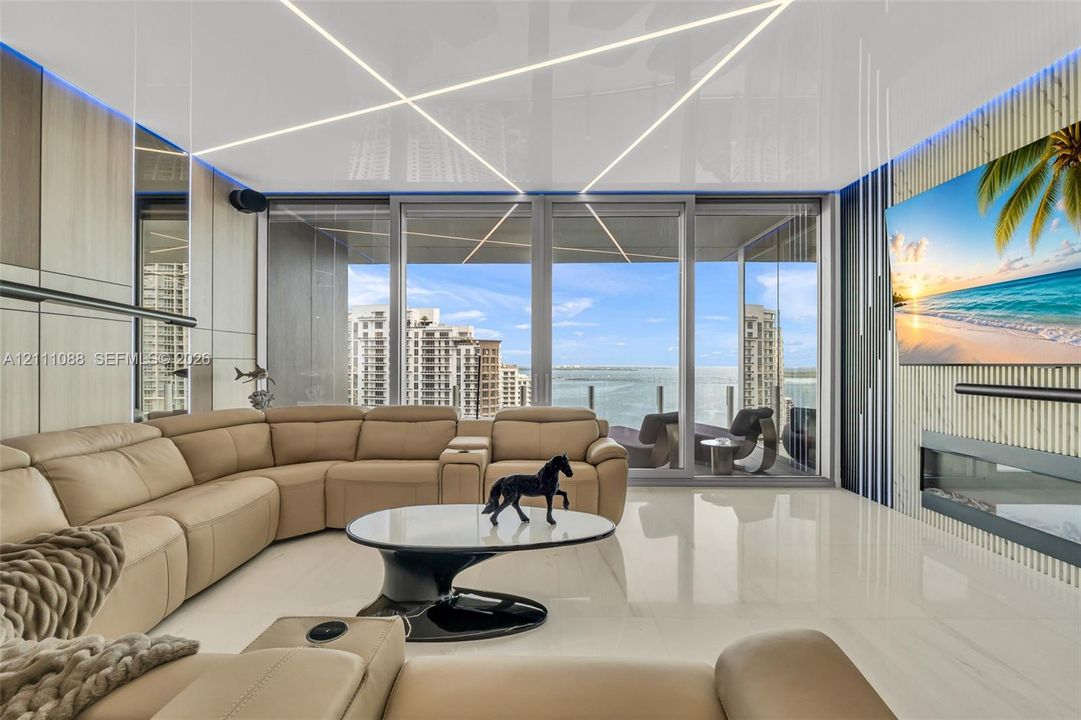 Living space featuring large-format tile flooring, linear ceiling lighting, floor-to-ceiling glass sliding doors, wood-finish wall paneling, and an integrated linear fireplace