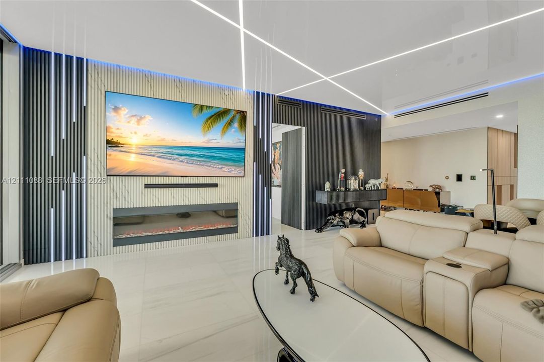 Feature wall with stone-finish cladding and integrated linear lighting, flush-mounted electric fireplace, vertical slat accent detailing, and large-format porcelain tile flooring