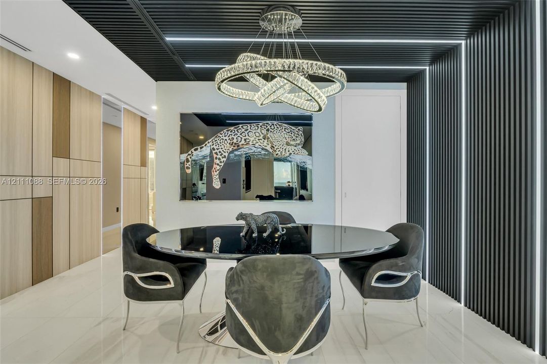 Contemporary space featuring a slatted black ceiling and wall accent, integrated linear LED lighting, large-format tile flooring, and a multi-tiered crystal ring chandelier