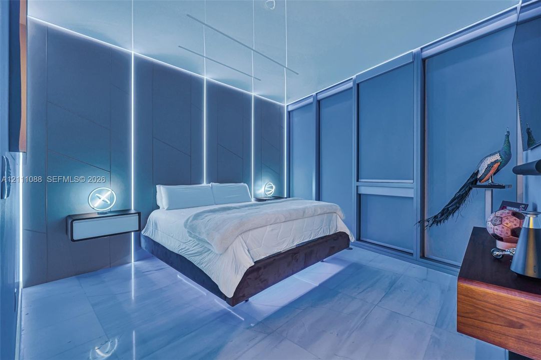 Custom-paneled wall with integrated vertical LED lighting, expansive floor-to-ceiling windows, and polished stone flooring