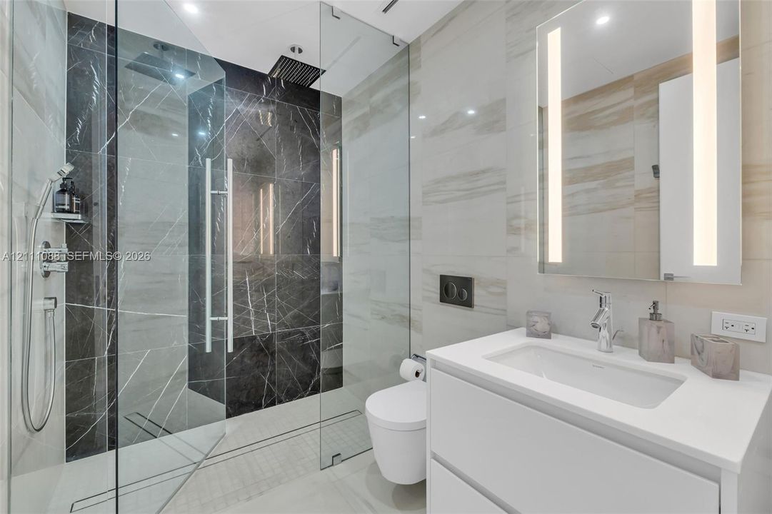 Walk-in shower featuring glass enclosure, rain-style showerhead, and dual-toned tile surround