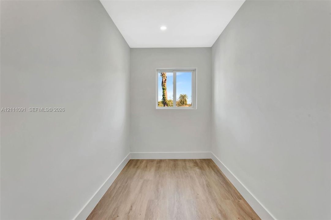 Neutral-toned interior space featuring wood-finish flooring, recessed lighting, and a square window
