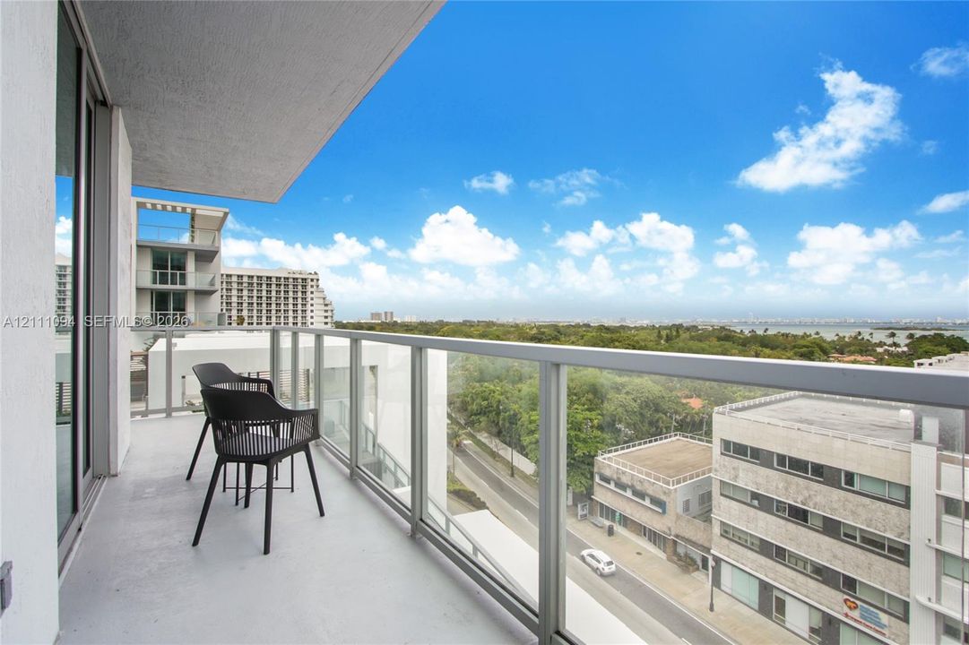 Covered private balcony featuring a glass panel railing and concrete flooring