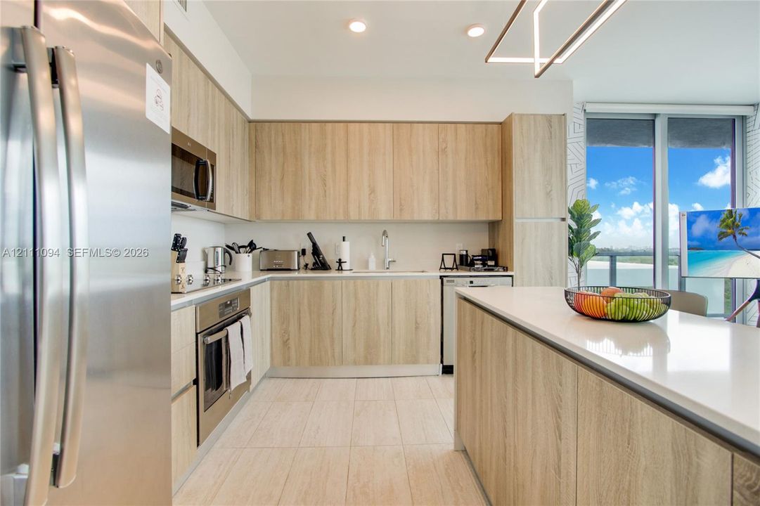 Kitchen featuring wood-finish cabinetry, stainless steel appliances, quartz countertops, a central island, and tile flooring