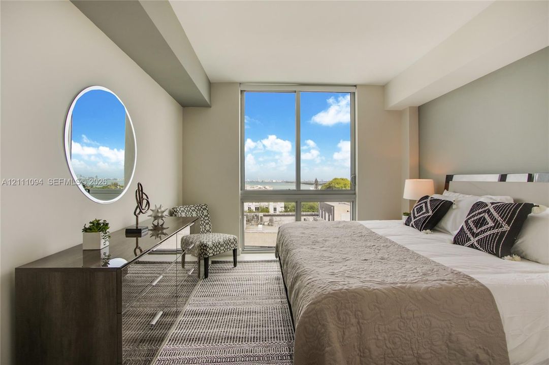 Floor-to-ceiling window featuring natural light, neutral wall finishes, and a circular wall-mounted mirror