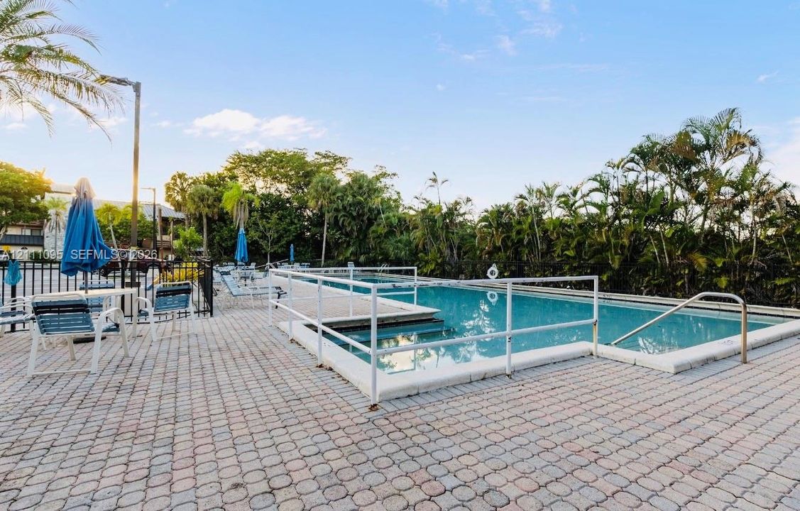 Swimming pool with white perimeter fencing, multi-level concrete decking, and integrated metal handrails