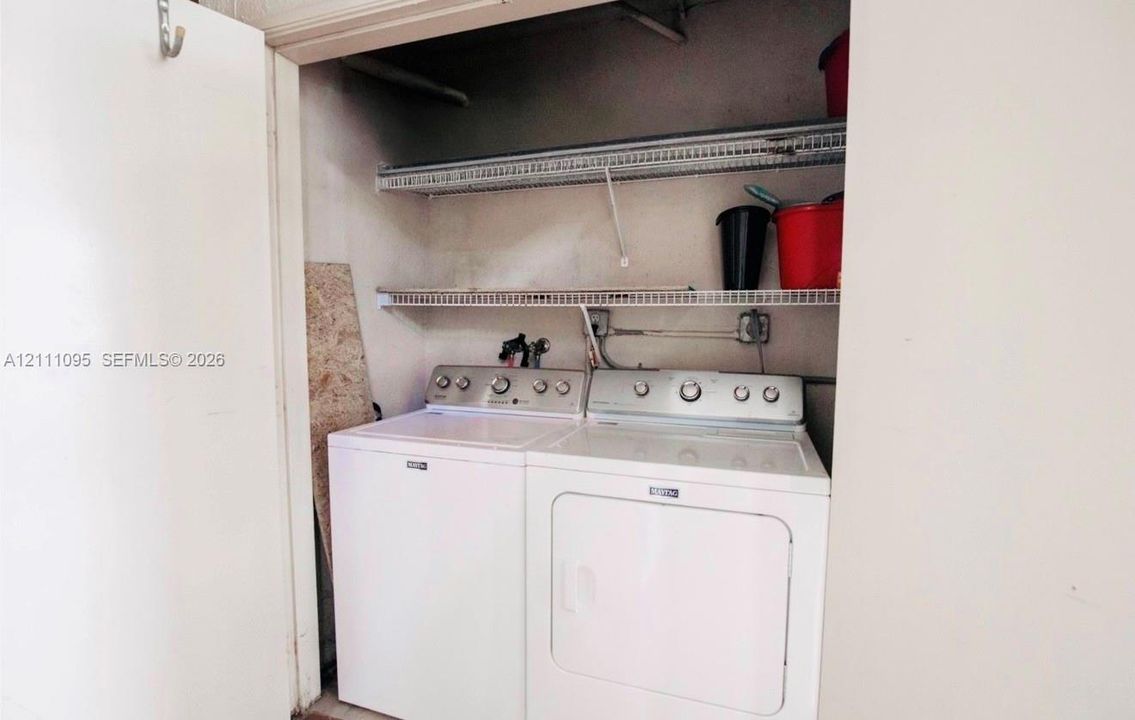 Utility closet featuring dual metal wire shelving units and dedicated laundry appliance hookups