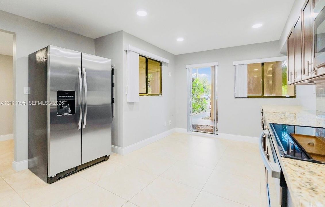 Kitchen featuring stone-finish countertops, stainless steel side-by-side refrigerator, tile flooring, and recessed lighting