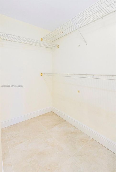 Walk-in closet featuring stone-finish tile flooring and multi-level wall-mounted wire shelving