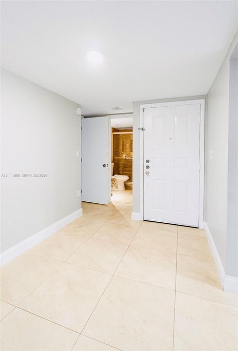 Neutral-toned interior featuring large-format light tile flooring, white panel doors, and recessed ceiling lighting
