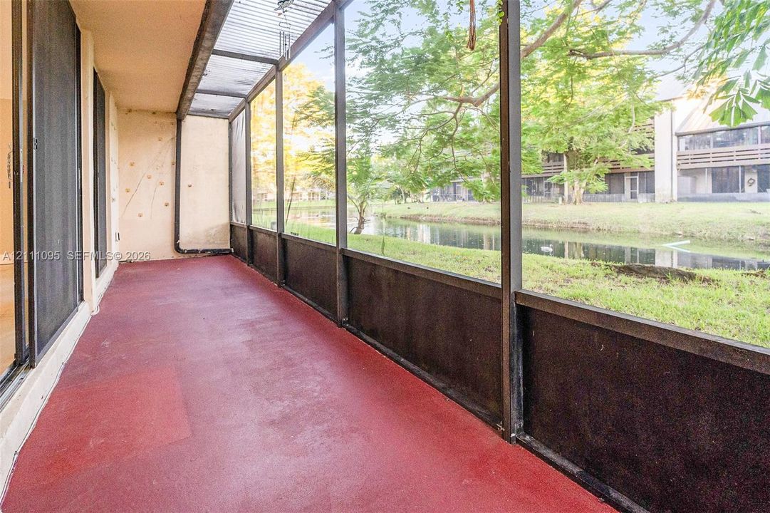Screened-in balcony with metal framing, concrete flooring, and water frontage